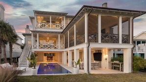 Une maison à deux étages avec une piscine, un espace salon extérieur et un escalier menant à l’étage supérieur.