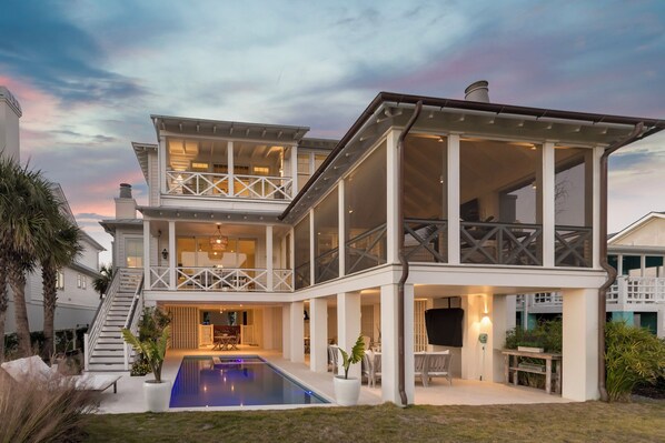 Una casa de dos pisos amb piscina, mobiliari d'exterior i una escala que mena al pis superior.