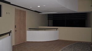 A hallway with a reception desk, a wooden door, and a window with blinds. - Asturias apartment for family or business (CERRITOS)