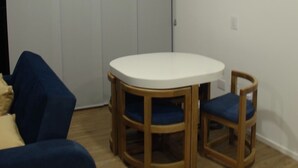 A room with a round wooden table and two matching chairs, a blue sofa, and a grey carpet. - Asturias apartment for family or business (CERRITOS)
