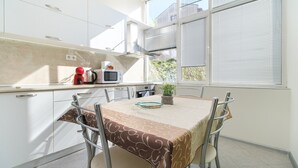 Una cocina moderna con armarios blancos, una mesa de comedor con mantel estampado y vistas al exterior a través de ventanas amplias.