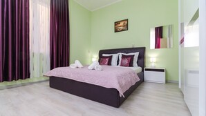 Un dormitorio con cama, mesita de noche, lámpara y un cuadro en la pared.