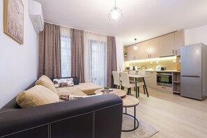 Een modern appartement met een zithoek, eethoek, kitchenette en een grote koelkast.