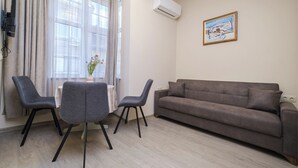 Un saló amb un sofà, dues cadires, una taula petita i una finestra amb cortines.