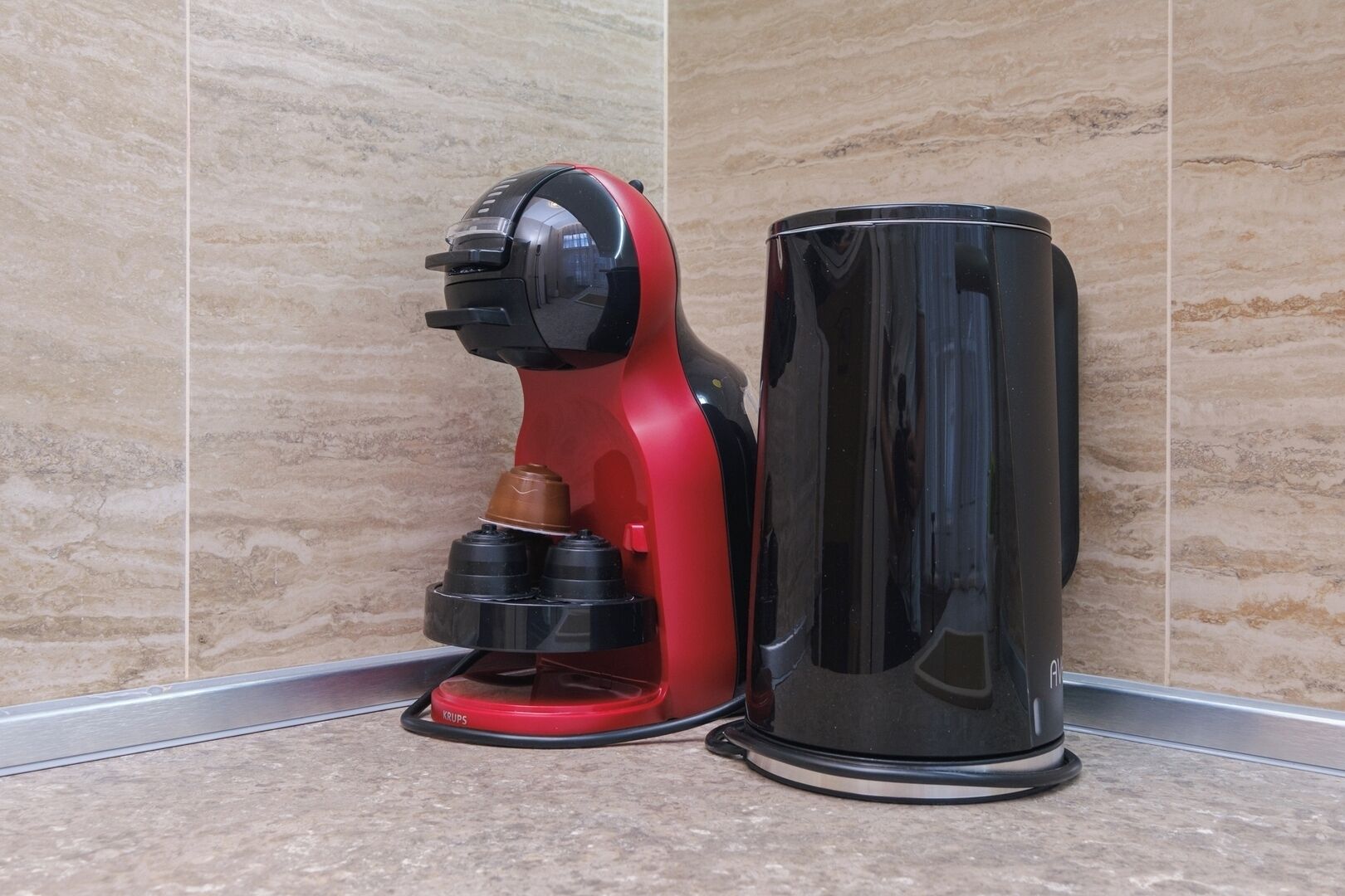 Kahvinkeitin ja vesiautomaatti laatoitetulla lattialla.