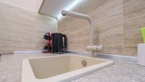 Un bany modern amb un lavabo integrat, un robinet i una cafetera al taulell.