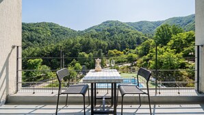 A balcony with a table and chairs overlooking a mountainous landscape.