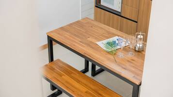 A wooden table with a bench, a menu, and a candle holder in a modern kitchen setting.