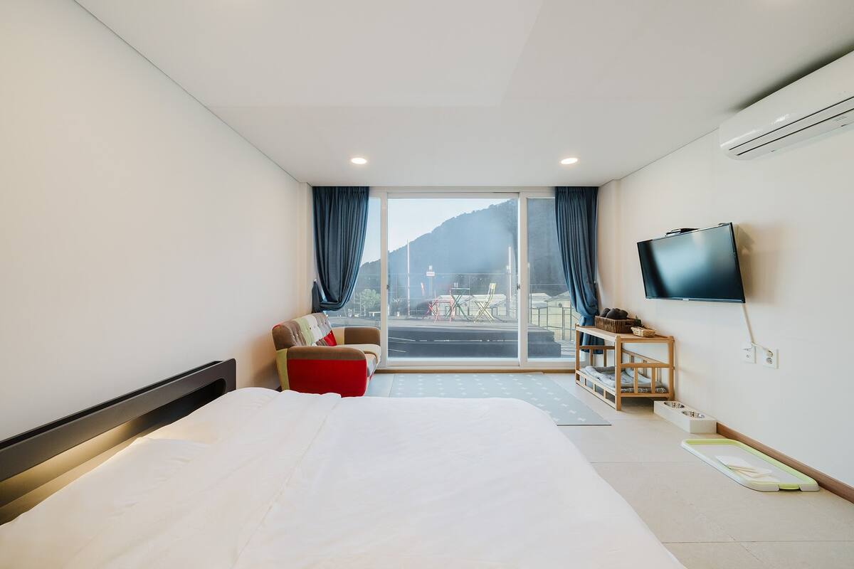 Une chambre d’hôtel avec un grand lit, une télévision, un canapé et une porte-fenêtre coulissante donnant sur un balcon.
