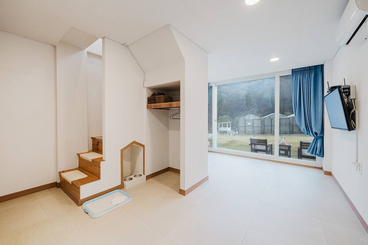 Un intérieur moderne avec un escalier, une grande fenêtre offrant une belle vue et un rideau bleu.