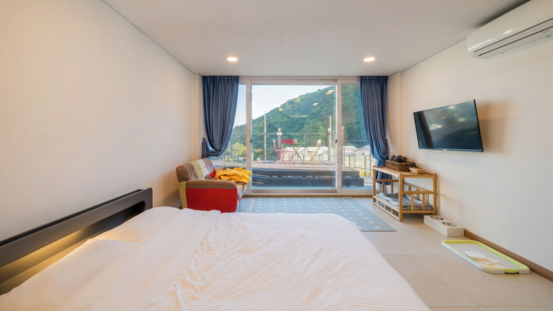 Une chambre d’hôtel comprenant un lit, une télévision, un canapé et un balcon aménagé avec du mobilier d’extérieur.