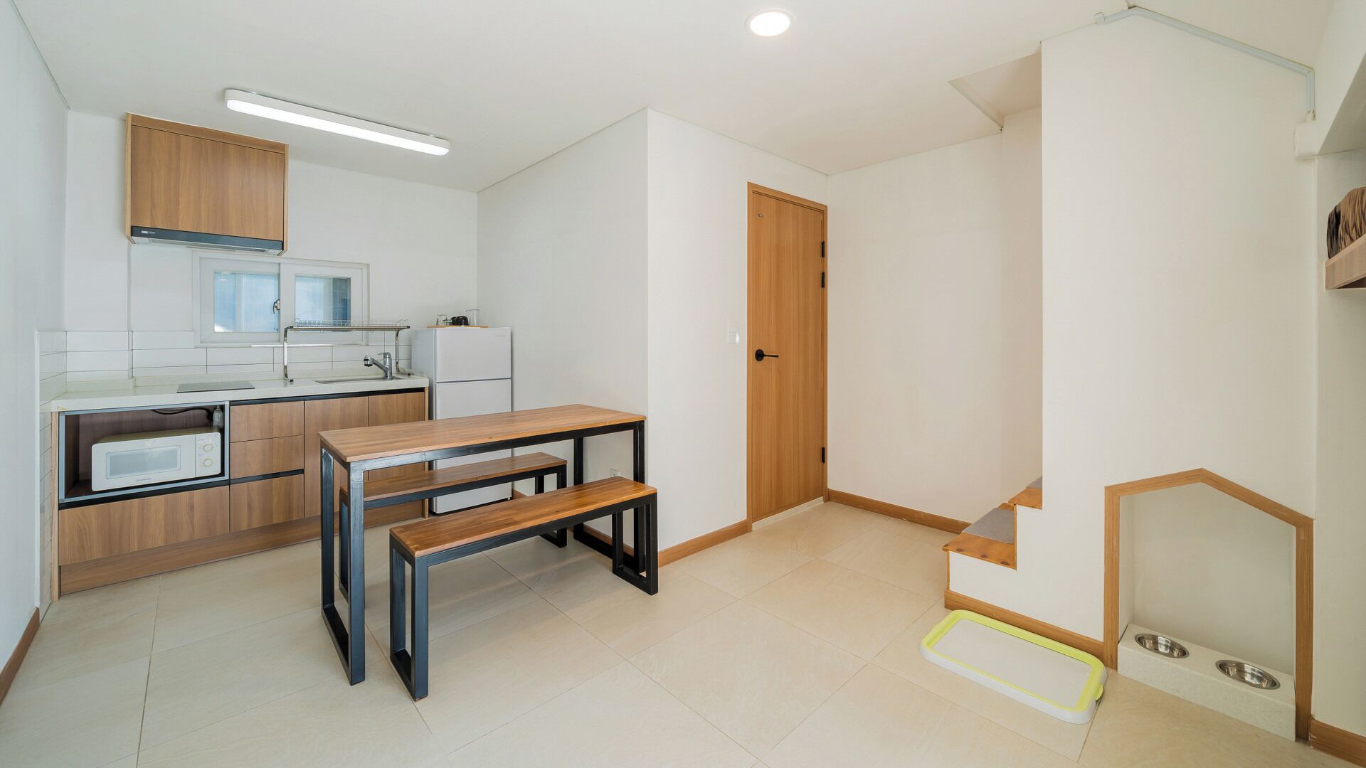 A compact kitchen with a microwave, refrigerator, and wooden cabinets.