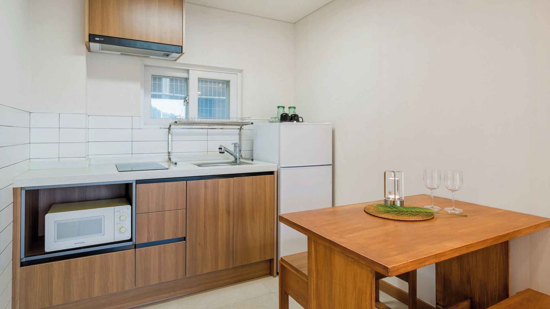 A compact kitchen with a microwave, sink, and wooden cabinets.