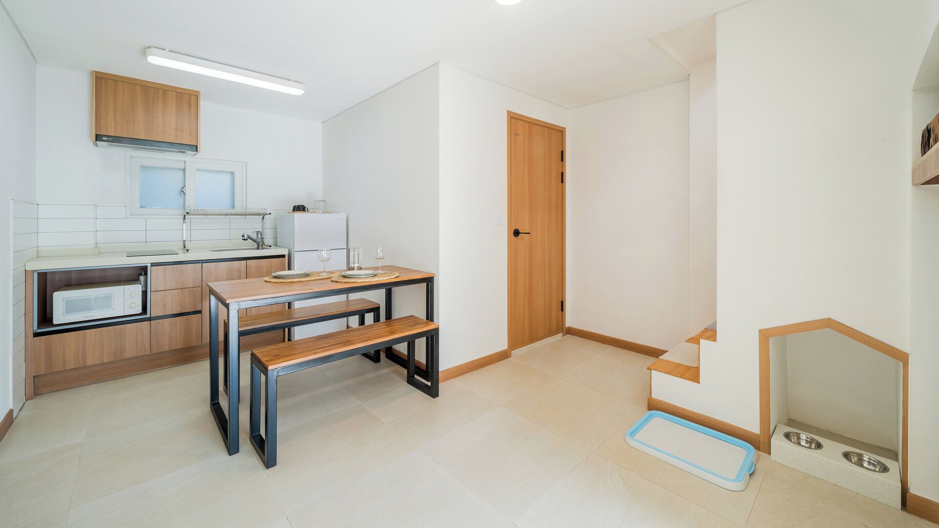 Cocina compacta con comedor, microondas, pileta y puerta de madera.