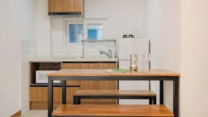A compact kitchen with a wooden table and bench, a window, and a refrigerator.
