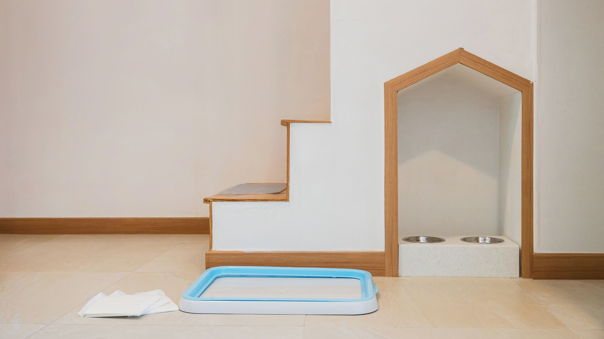 Una habitación con escalera de madera, comedero para mascotas y una cama para mascotas.