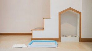 Ein Zimmer mit einer Holztreppe, einer Futtermiststation und einem Haustierbett.