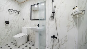 A bathroom with a toilet, sink, and shower area.