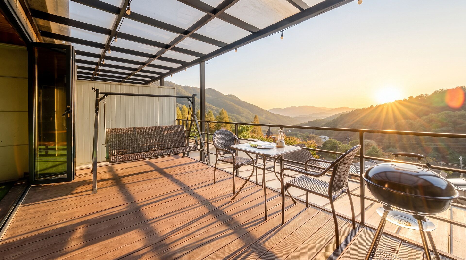 Un balcón con piso de madera, una mesa, sillas, una parrilla y vistas a las montañas.