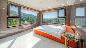 Un dormitorio con cama, mesita de noche y vistas a montañas.