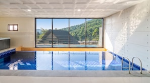 Una piscina interior con vistas a un paisaje montañoso a través de amplios ventanales.
