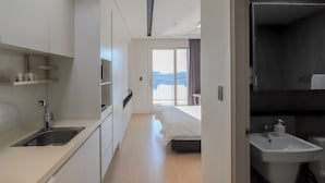 Ein modernes Hotelzimmer mit Küchenzeile, einem Bett und einem Badezimmer.