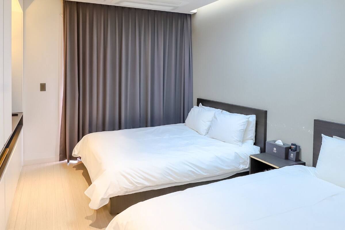 Una habitación de hotel con dos camas, una mesita de noche, un control remoto y una caja de pañuelos.