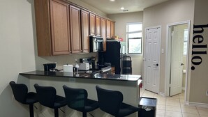 A modern kitchen with wooden cabinets, a black countertop, and three bar stools.