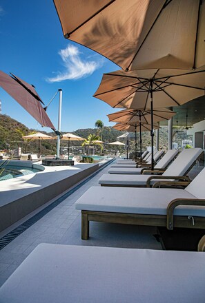 A poolside area with sun loungers and umbrellas, a pool, and a view of hills. - D'Vine Paradise - Luxe 2BR/2BA Retreat/Rooftop Pool & Spa (Puerto Vallarta)