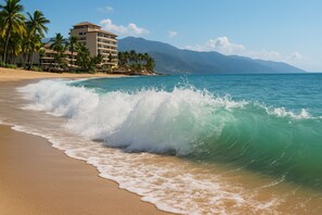 A beach with waves, palm trees, and a hotel in the background. - D'Vine Paradise - Luxe 2BR/2BA Retreat/Rooftop Pool & Spa (Puerto Vallarta)