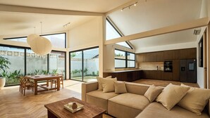 A spacious living area with a large sofa, a dining table, and a kitchen area. - White Villa by Betterplace (Bengkel)
