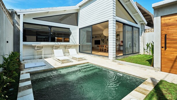 A modern house with a swimming pool, outdoor seating, and a large glass door leading to the interior. - White Villa by Betterplace (Bengkel)