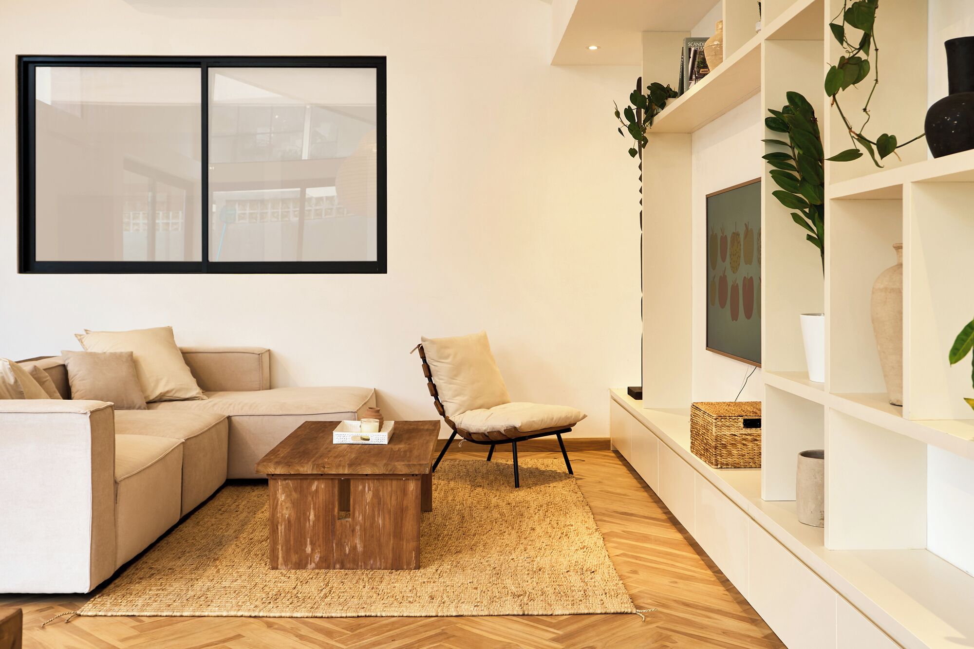 Een moderne woonkamer met een hoekbank, een houten salontafel, een stoel en een groot raam.