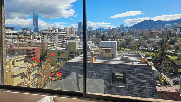 Un paysage urbain caractérisé par un gratte-ciel imposant, une diversité de styles architecturaux et un arrière-plan montagneux.