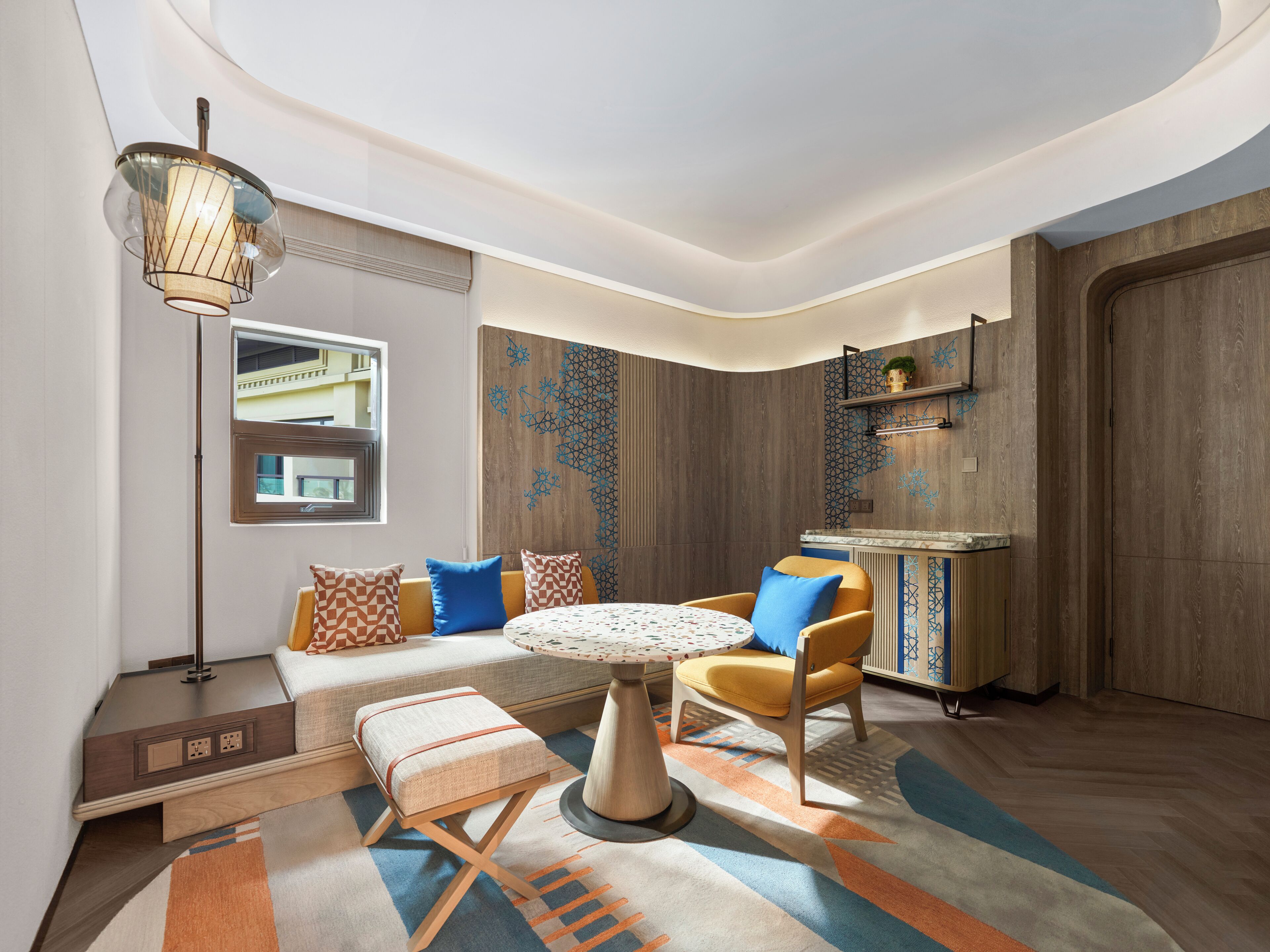 A modern interior with a round table, sofa, and chairs, a floor lamp, and a patterned rug.