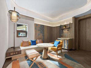 Un intérieur moderne avec une table ronde, un canapé et des fauteuils, un lampadaire et un tapis à motifs.