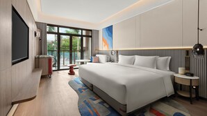 A modern hotel room with a large bed, a flat-screen TV, a dining area, and a view of the outdoors. - Dhawa Beihai Weizhou Island (Beihai)