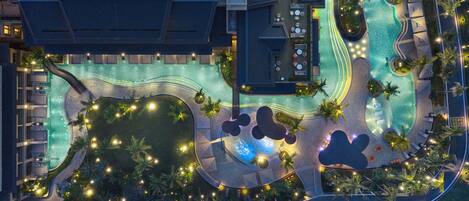 Vista aérea de un resort con piscina, palmeras y zonas de estar al aire libre.
