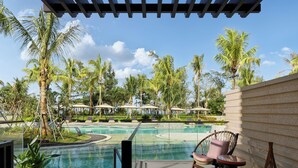 A pool area with lounge chairs and umbrellas, surrounded by palm trees and a clear sky. - Dhawa Beihai Weizhou Island (Beihai)