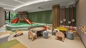 Zona infantil con tobogán, piscina de bolas y diversos juegos.