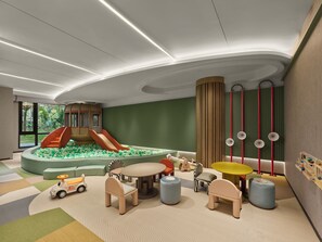 Zona infantil con tobogán, piscina de bolas y diversos juegos.