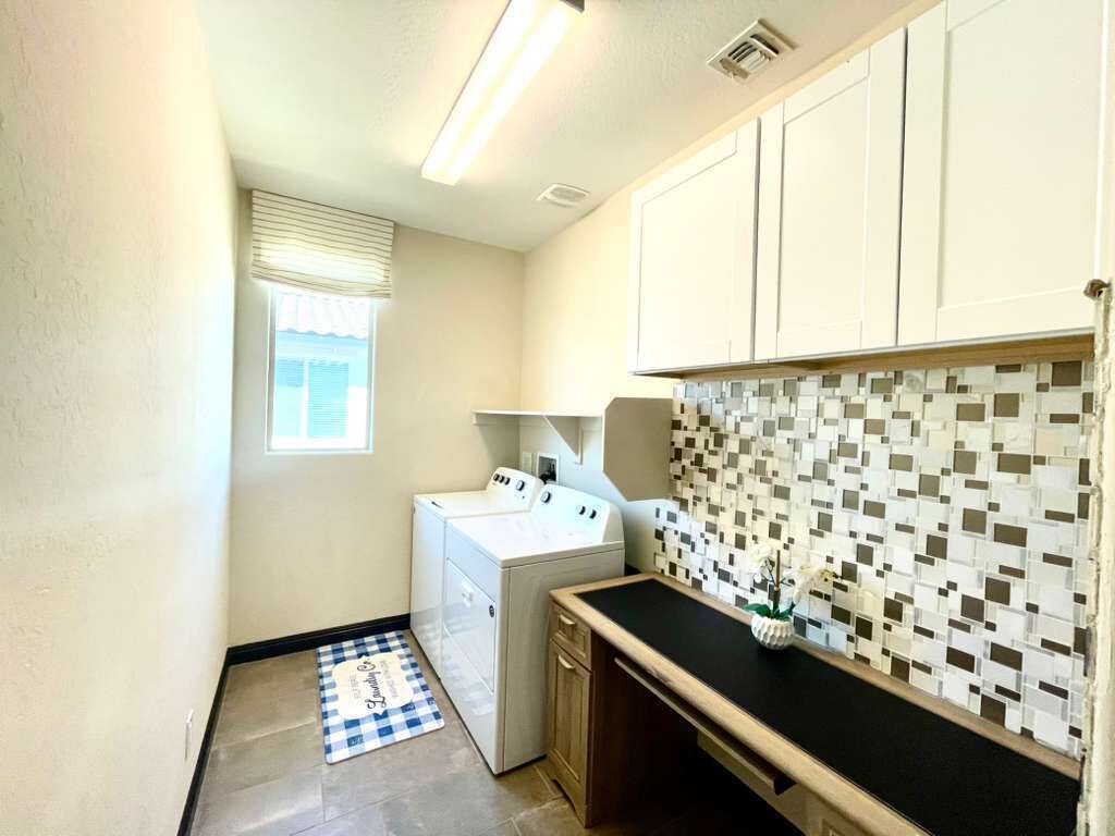 A laundry room with a washing machine, dryer, and a tiled backsplash.
