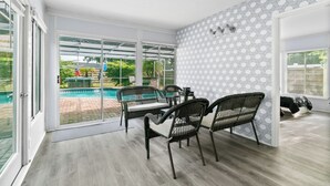A spacious room with a view of a swimming pool, a dining area with wicker furniture, and a patterned wall. - Spacious 4-bedroom house in wonderful Sarasota with AC (Sarasota)