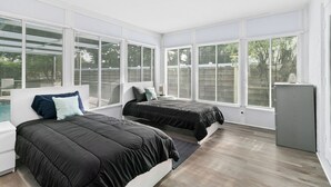 A modern bedroom with two beds, large windows, and a small refrigerator. - Spacious 4-bedroom house in wonderful Sarasota with AC (Sarasota)