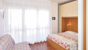 Un dormitorio con una cama, un armario de madera, una mesita y un sofá.