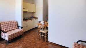 Un espacio habitable compacto con kitchenette, comedor y sofá.