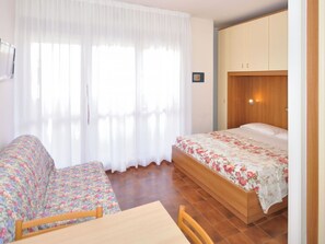 A bedroom with a bed, a wooden wardrobe, a small table, and a sofa. - Nice apartment for 3 people with A/C, WIFI, TV, balcony and pets allowed (San Michele Al Tagliamento)