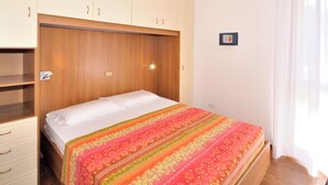 A bedroom with a bed, wooden wardrobe, and a small picture on the wall. - Cosy apartment for 6 people with WIFI, A/C, TV, balcony and pets allowed (San Michele Al Tagliamento)
