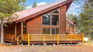 A log cabin with a porch, large windows, and a metal roof. - Aspen Inn just 20 minutes from Yellowstone National Park (Island Park)