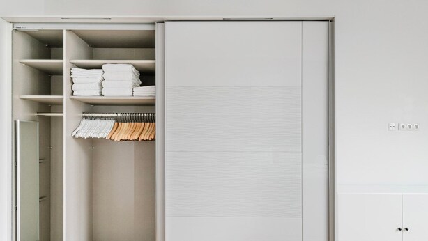 Ein begehbarer Kleiderschrank mit Regalen, Kleiderstangen und einem Spiegelbereich.